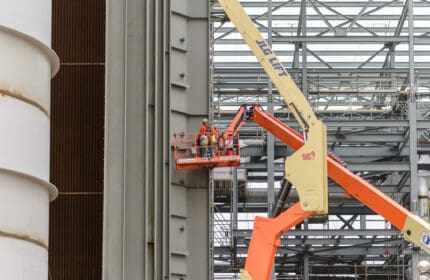Worker on JLG scissors lift to work on exterior metal structure