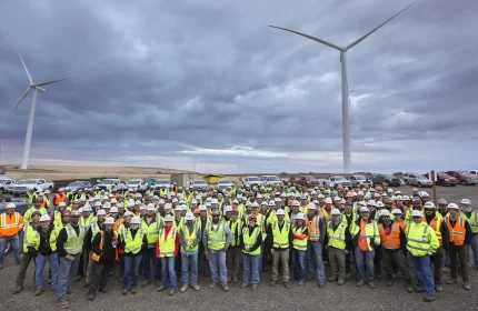 Portland General Electric Company - Tucannon River Wind Farm - Group of Employees Standing in Parking Lot Beneath Two Wind Turbines